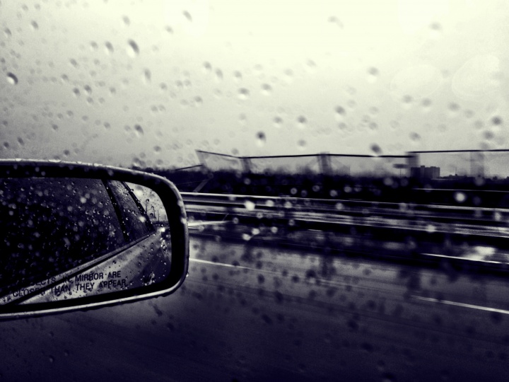 Car side mirror raining outside.