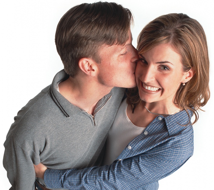 A young man kissing a young woman who is hugging him.