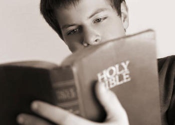 A teen boy looking at a Bible.