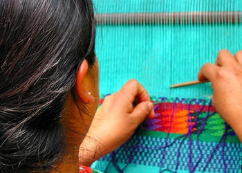 A woman weaving on a loom.