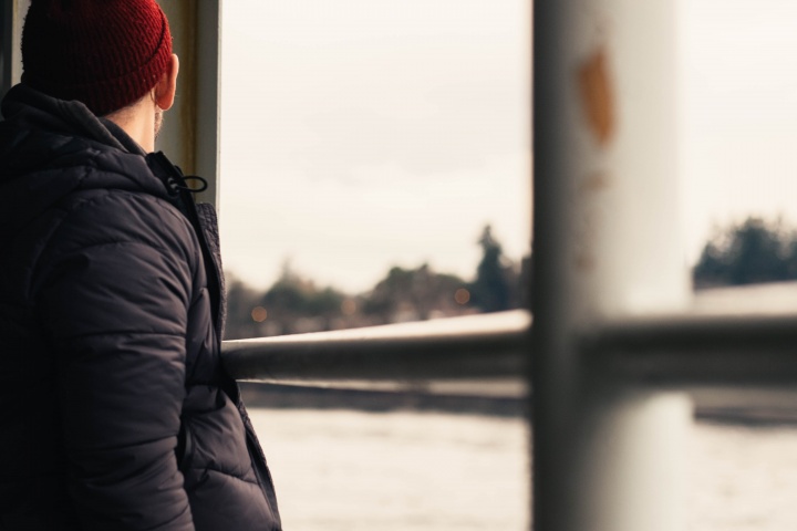 A young man look out a window at the snow.