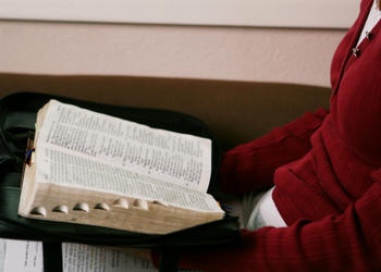A woman reading a Bible on her lap.