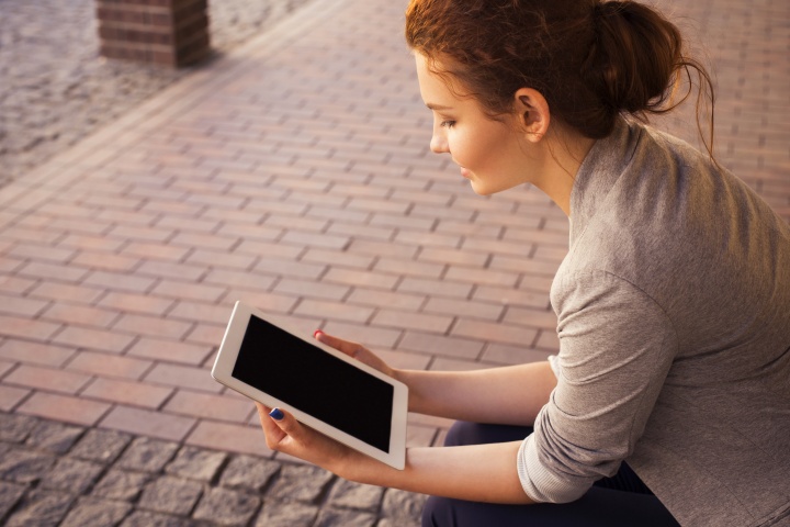 A young woman reading on a tablet device.