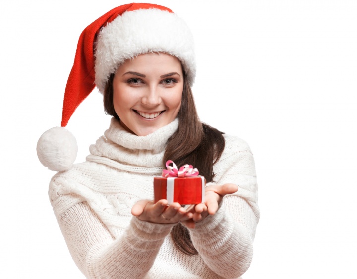 A woman wear a Christmas stocking cap holding a gift.