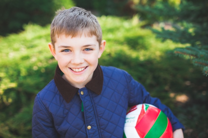 A young boy holding a ball and smiling.