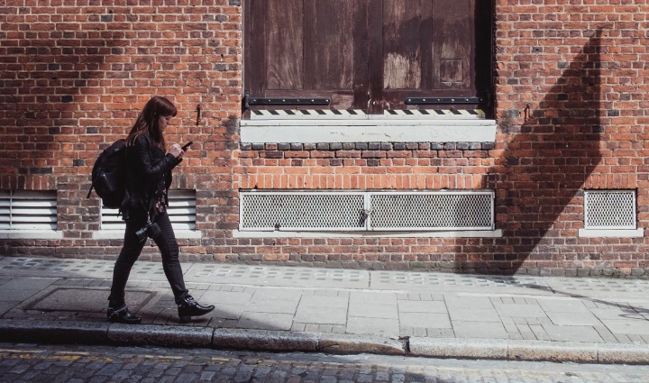 A woman walking by an old brick building.