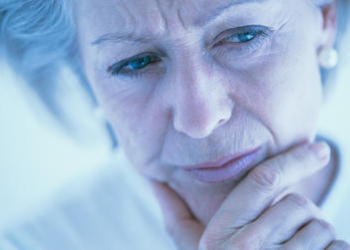 A older woman with her hand holding her chin - as if thinking.