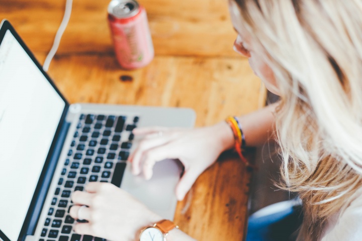 A woman typing on a Mac laptop.