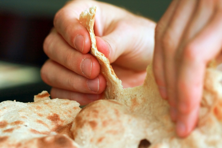 A person pulling apart some flat bread,