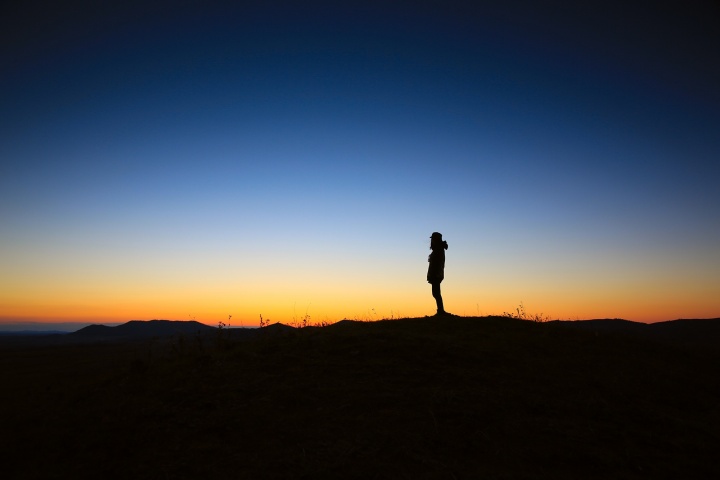 A person standing by thelselves with a colorful sunset.