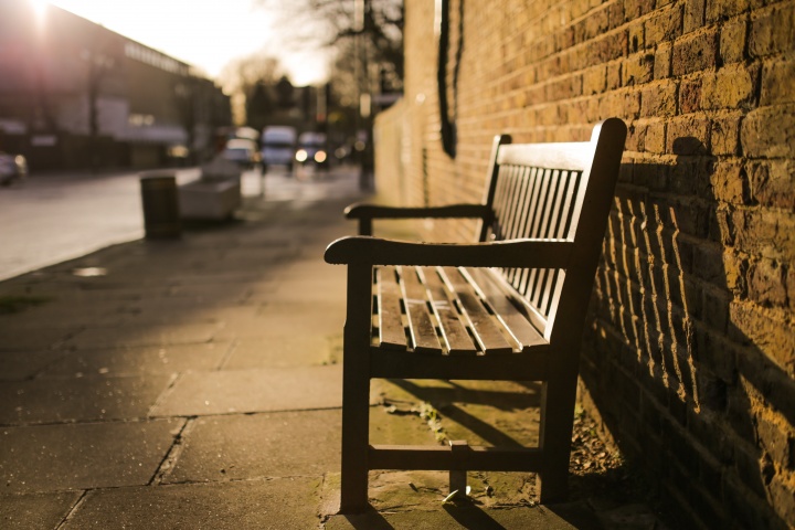 A empty bench on a sidewalk.