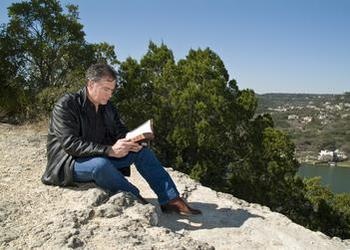 A man reading a Bible sitting outside.