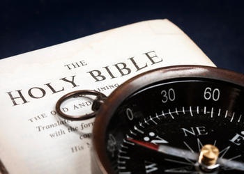 A compass on top of a Bible.