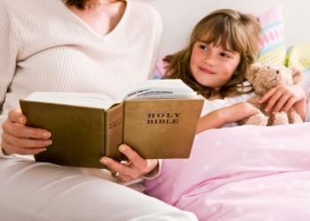 Mother reading Bible to child in bed - Teaching Youth Religious Values