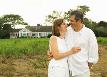 A married couple in front of a house.