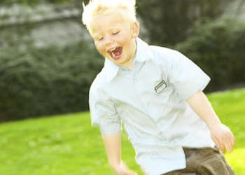 A little boy running on the grass.