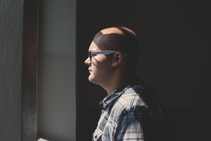 A man wearing glasses looking out a window.