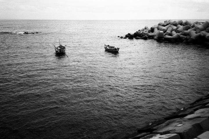 Small boats sitting in the bay of a sea.