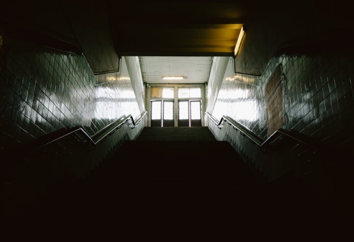 Dark stairs leading up to doors where light is coming through.