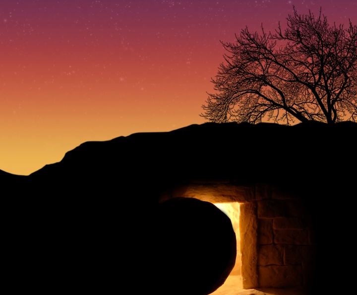 A tomb cut out of rock with a round stone next to the entrance.