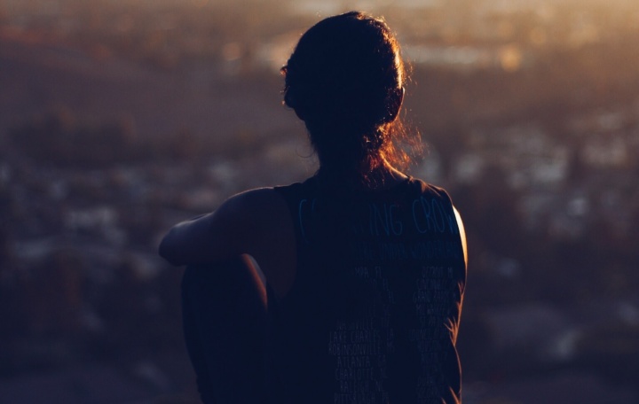 A young woman sitting on top of a rock.