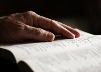 An older person's hand on a Bible.