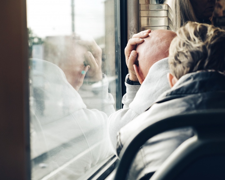 A man leaning up against a window holding his head.