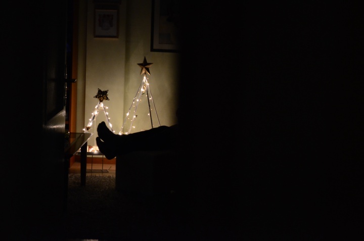 A person sitting in a dark room with Christmas lights.