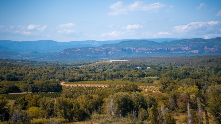 A landscape in France with rolling mountains in the distance and greenery in the foreground.