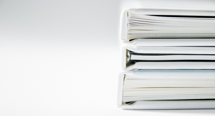 Photo of documents in stacked binders on white table.