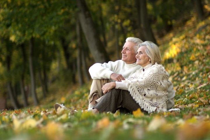 an older couple sitting outdoors amongst the leaves and trees