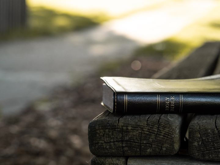 Bible laying on a park bench.