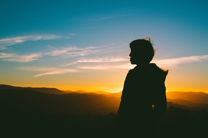 A silhouette of person has the sun is setting.