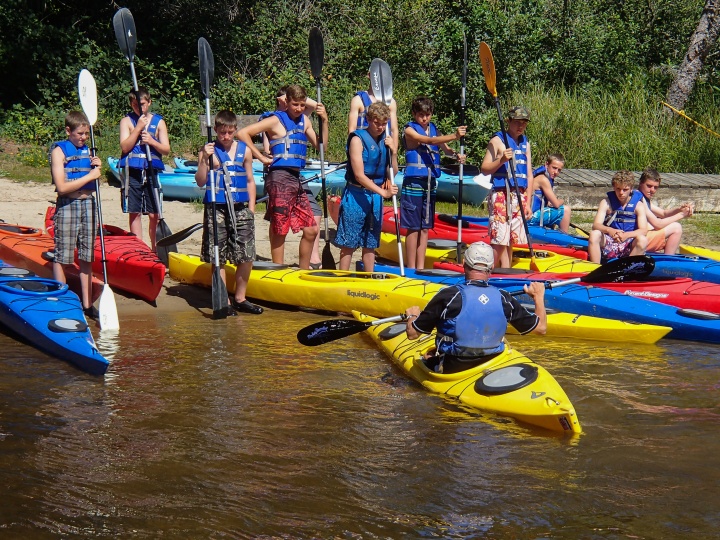 Campers getting ready to go on a kayak trip down the river. 