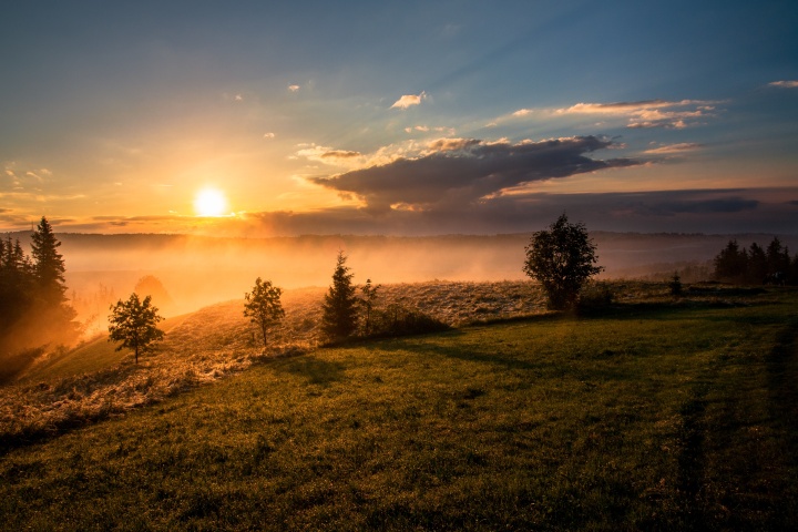 Photo of a sunset over the mountains with fog.