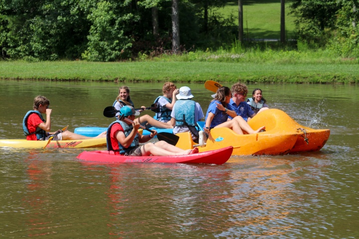 a group of boys and girls in kayaks and paddleboat