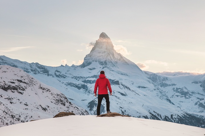 Photo of a man standing in front of a snowy mountain.