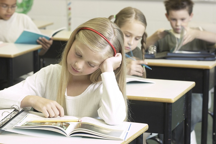 A girl looking at her school book.