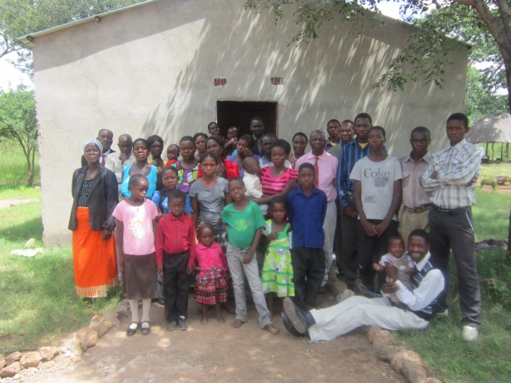 A group shot of the congregation in Mapoko. Behind them is the church building the brethern built.