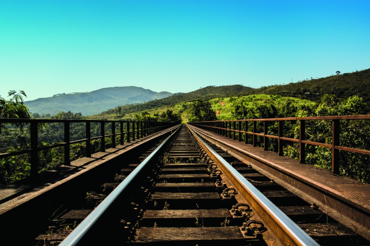 Photo of train tracks disappearing forward into the distant mountains.