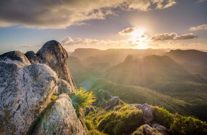 Photo of the sun shining over a mountain.