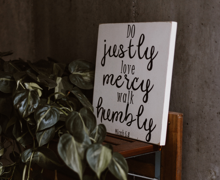 Photo of sign surrounded by a leafy tree, with Micah 6:8 painted on it.