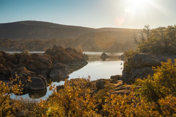 a landscape with a lake, rocks, and rolling hills