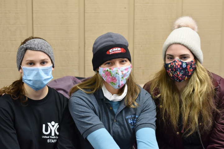 Three ladies on nursing staff at winter camp smile with masks on.