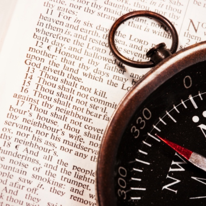 Compass laying on top of a Bible opened to Exodus 20 - where the 10 Commandments are listed.