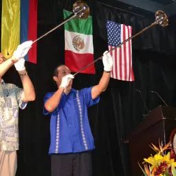 Men blowing horns against a backdrop of various countries' flags