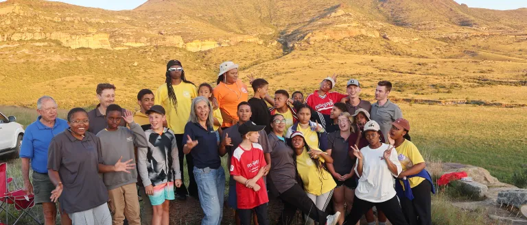 a group of people standing in front of low rolling mountains