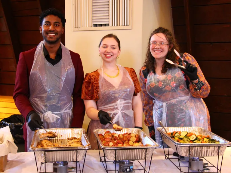 Young adults preparing the meal a man and two women preparing a meal