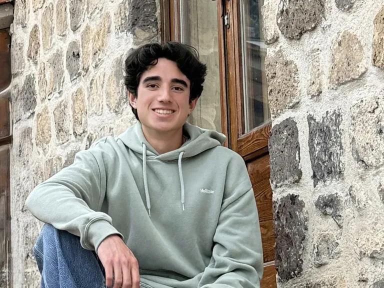 a young man sitting in front of a brick wall