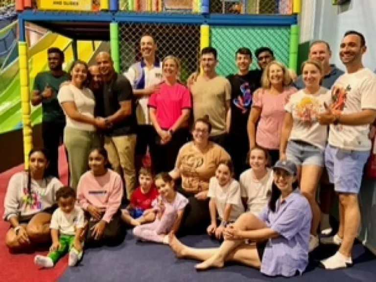 a group of people seated and standing indoors at a playground